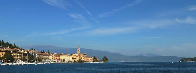 Trip Bosnien Herzegowina beliebte Urlaubsziele am Gardasee -  Mit einer Fläche von 370 km² ist der Gardasee der größte See Italiens. Es liegt am Fuße der Alpen und erstreckt sich über drei Staaten: Lombardei, Venetien und Trentino. Die maximale Tiefe des Sees beträgt 346 m, er hat eine längliche Form und sein nördliches Ende ist sehr schmal. Dort ist der See von den Bergen der Gruppo di Baldo umgeben. Du trittst aus deinem gemütlichen Hotelzimmer und es begrüßt dich die warme italienische Sonne. Du blickst auf den atemberaubenden Gardasee, der in zahlreichen Blautönen schimmert - von tiefem Dunkelblau bis zu funkelndem Türkis. Majestätische Berge umgeben dich, während die Brise sanft deine Haut streichelt und der Duft von blühenden Zitronenbäumen deine Nase kitzelt. Du schlenderst die malerischen, engen Gassen entlang, vorbei an farbenfrohen, blumengeschmückten Häusern. Vereinzelt unterbricht das fröhliche Lachen der Einheimischen die friedvolle Stille. Du fühlst dich wie in einem Traum, der nicht enden will. Jeder Schritt führt dich zu neuen Entdeckungen und Abenteuern. Du probierst die köstliche italienische Küche mit ihren frischen Zutaten und verführerischen Aromen. Die Sonne geht langsam unter und taucht den Himmel in ein leuchtendes Orange-rot - ein spektakulärer Anblick.